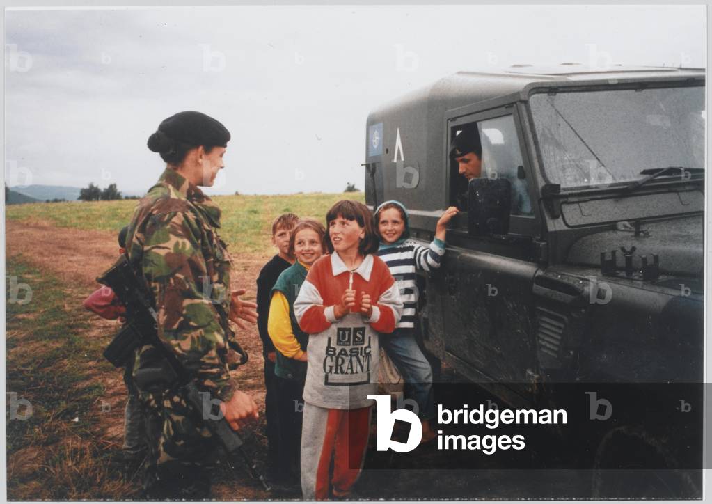 Capt Mason and Bdr Adie (in a vehicle), with one of the local children, Kosovo, 31 May- 20 Aug 1999 (photo)
