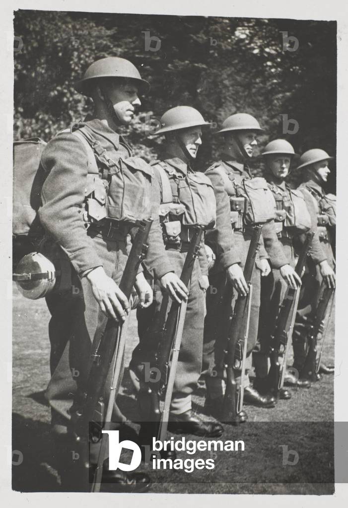 Divisional Guard: A line of armed men wearing tin helmets, and carrying their kit (b/w photo)