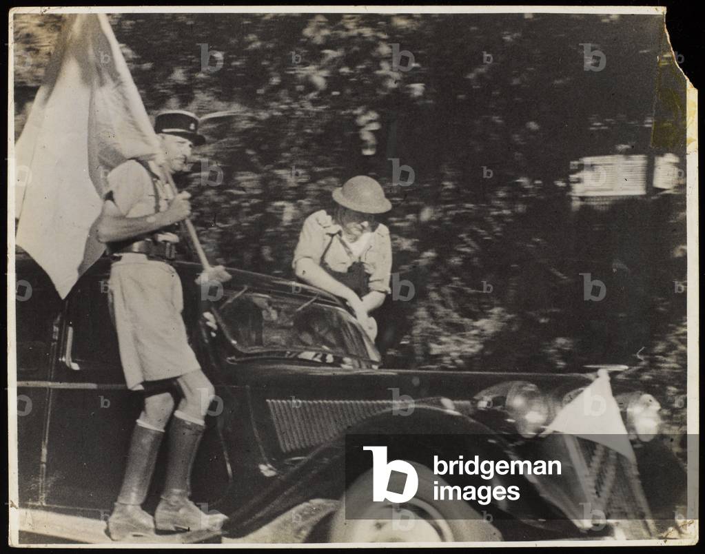 A French officer holding a flag of truce while being driven around the town of Majunga, 10 September 1942 (b/w photo)