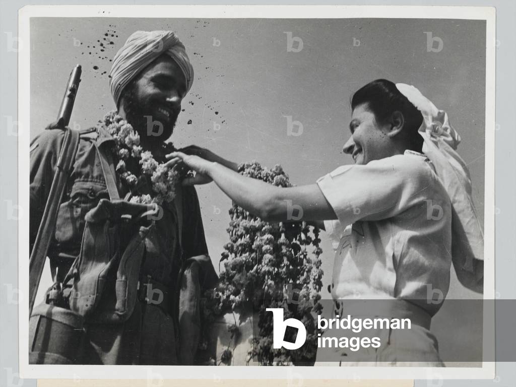 A Sikh soldier receives a garland of flowers from a nurse, 1946 circa (b/w photo)