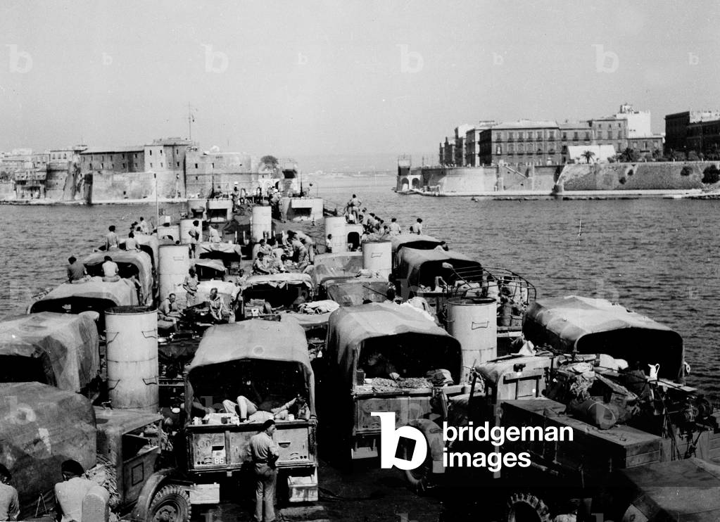 Landing Ship Tank heavily loaded with trucks and a recovery vehicle approaching Taranto, Italy, 1943 (b/w photo)