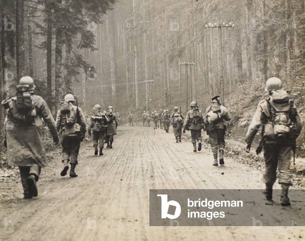 US 7th Army infantryman march through a forest, 1945 (b/w photo)