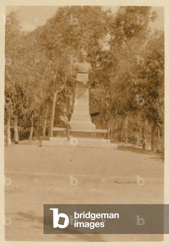 A British soldier sitting at the base of a statue in Alexandria, Egypt, 1916 (b/w photo)