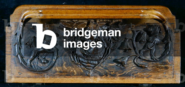 A misericord depicting an ape's head peeping out from a large shell which is framed in foliage, New College Chapel, Oxford, late 14th century (wood)