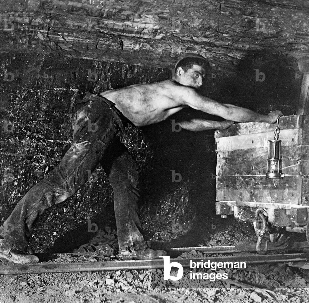 Worker pushing a cart in a mine (b/w photo)