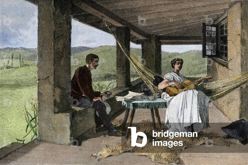 A young Hispanic woman (chicano or latino) playing guitar in a hammock, settles under the portico of a ranch in Texas or California, around 1800. By his side a man smokes near a table where newspapers and a service are posed. Colour engraving, 19th century.