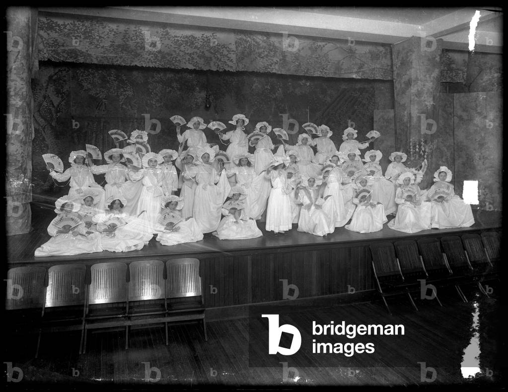 Group of little girls posed on a small stage holding fans, probably the Roman Catholic Orphan Asylum, Kingsbridge, Bronx, c.1911 (b/w photo)