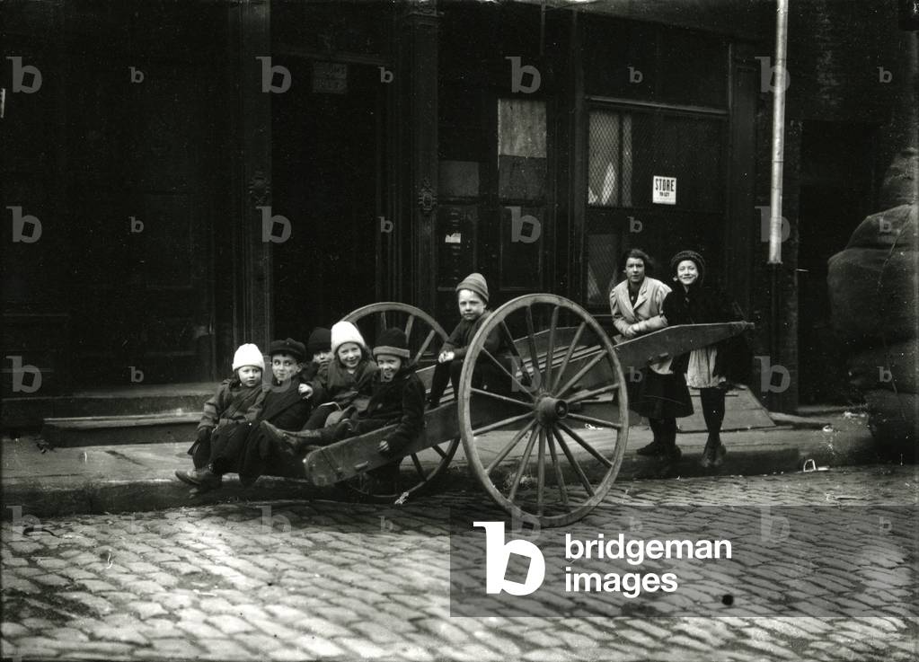 Group of children in cart, with girl and woman standing behind, c.1910-21 (b/w photo)