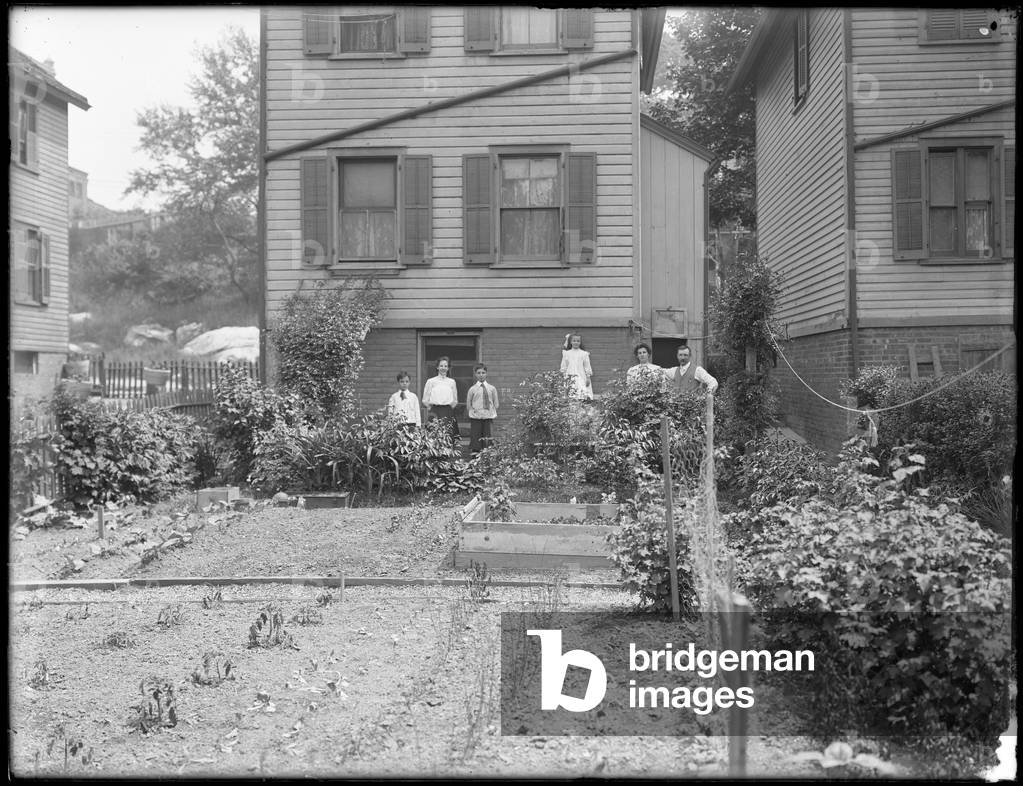 Family poses beside their backyard vegetable garden, Inwood, New York, c.1910 (b/w photo)