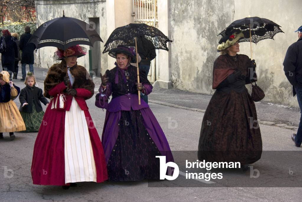 Three ladies in Victorian costumes with sun umbrellas