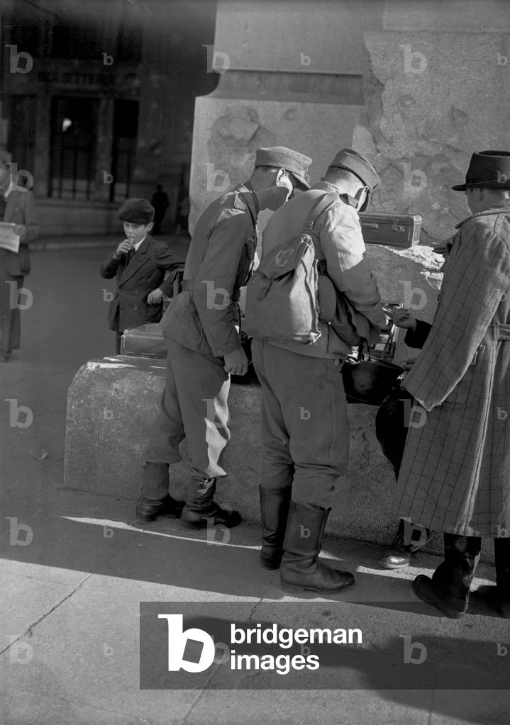 Members of the German occupation forces buying souvenirs in front of the railway station in Milan, 1944 (b/w photo)