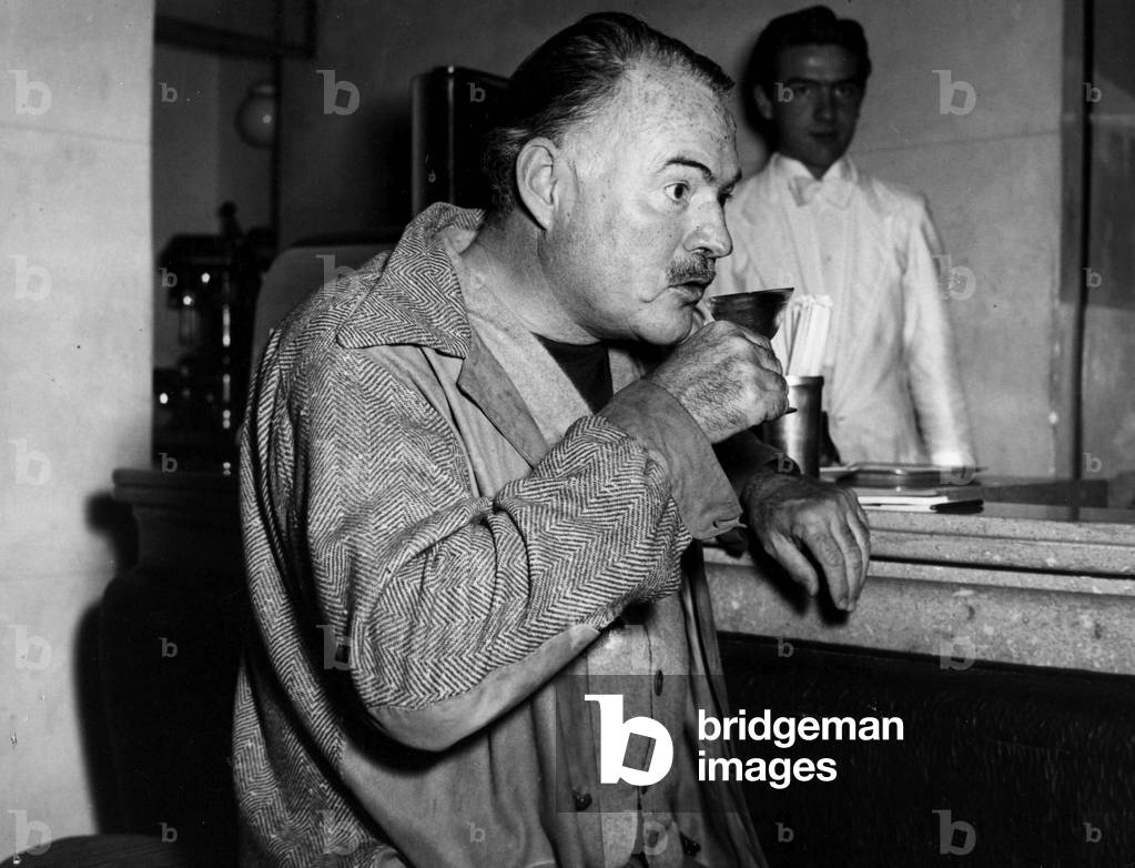 Ernest Hemingway at the bar counter of a hotel during his holiday on Lake Maggiore, Italy, 1948 (b/w photo)