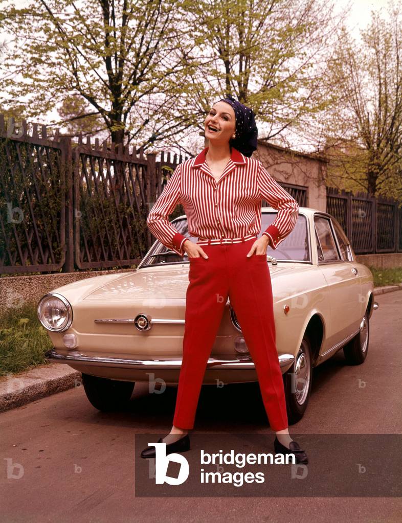 A model posing in front of a Fiat 850 coupe car, 1965 (photo)