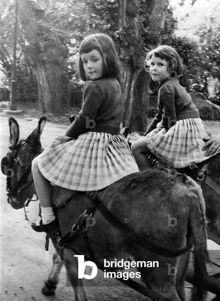 Isabella and Isotta Rossellini on donkeys at Villa Borghese, Rome, 1957 (b/w photo)