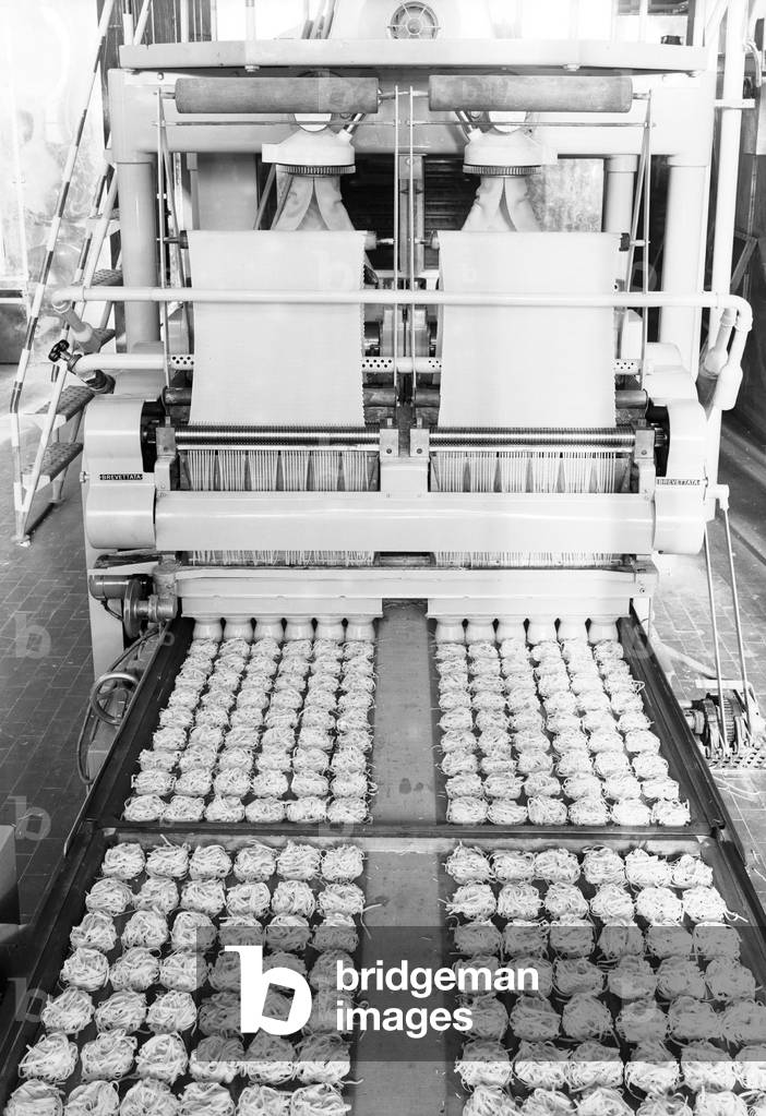 Assembly line machine used to cut fresh pasta, Italy, 1958 (b/w photo)