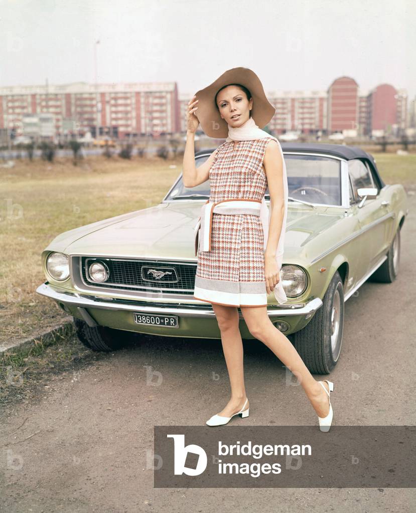 Model posing next to a Ford Mustang, 1968 (photo)