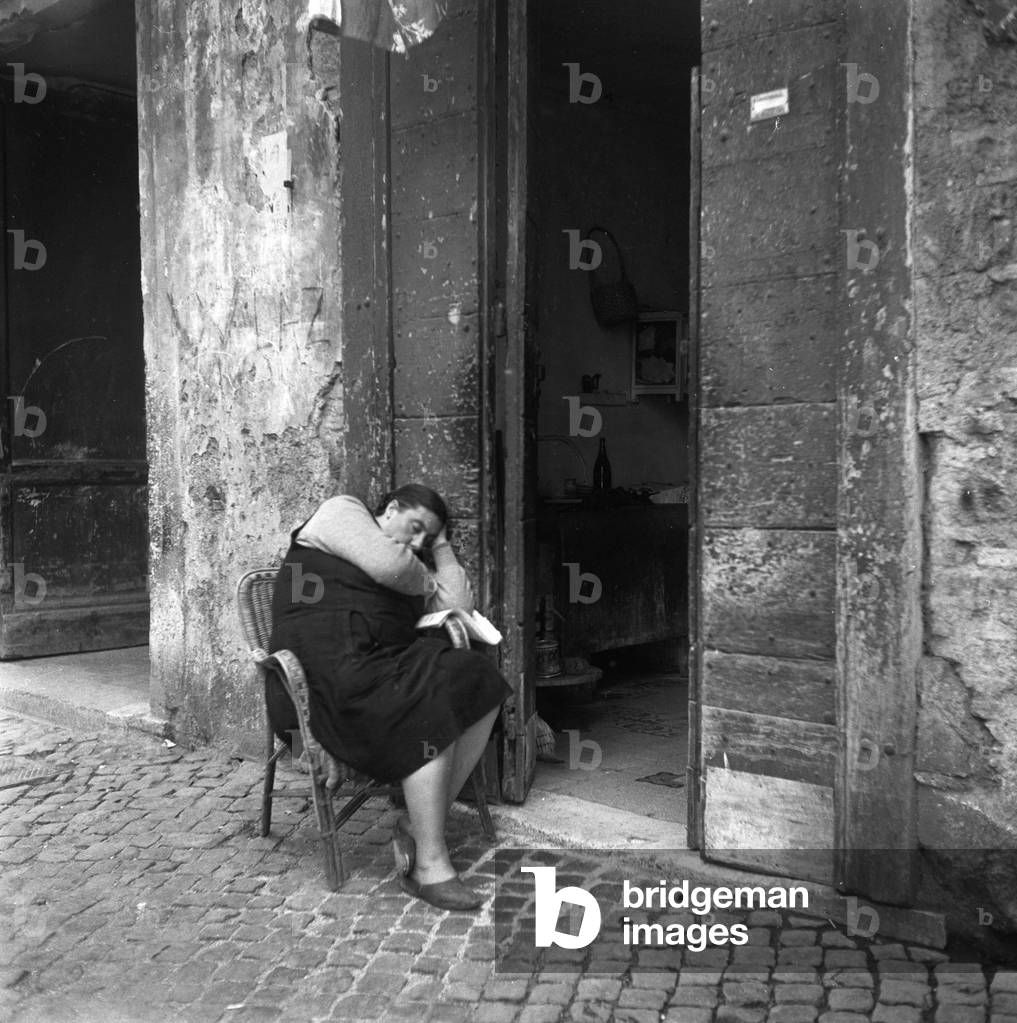 Rome 01/06/1954. Une femme assise se repose sur le seuil de sa maison. (sieste)