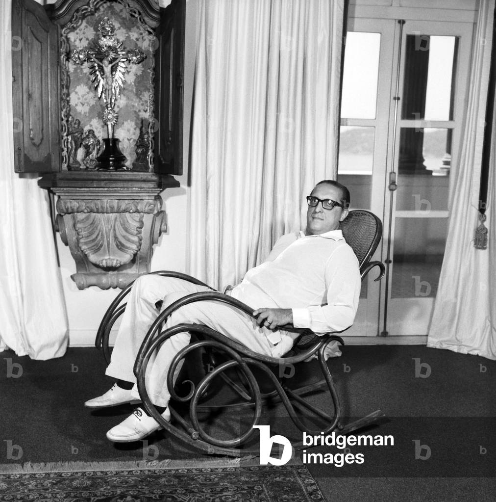 Carlos Lacerda sitting on a rocking chair, Rio de Janeiro, Brazil, 1964 (b/w photo)