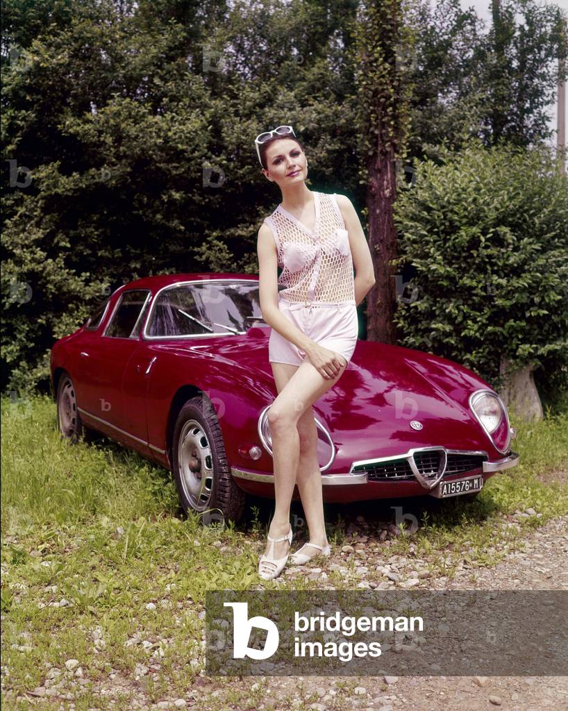 A model posing in front of an Alfa Romeo Giulia TZ Zagato, 1965 (photo)