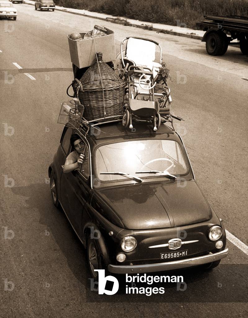 Italian family in a fiat 500 loaded with luggage, 1970s (b/w photo)