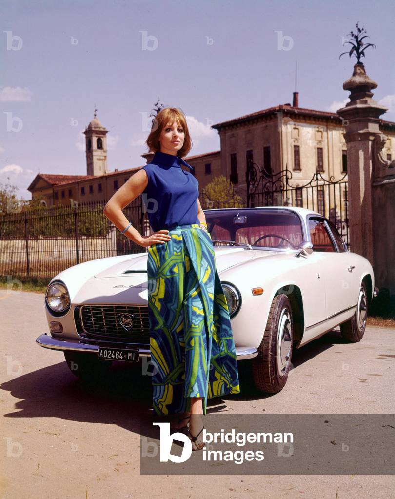 A model posing in front of a Lancia Flaminia Berlinetta Zagato, 1965 (photo)
