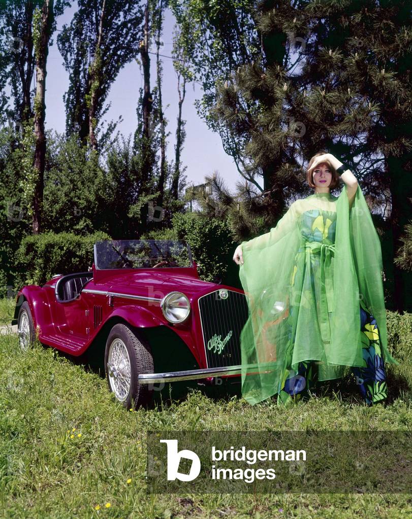 A model wearing a kimono posing in front of an Alfa Romeo Spider 1750 Zagato, 1965 (photo)