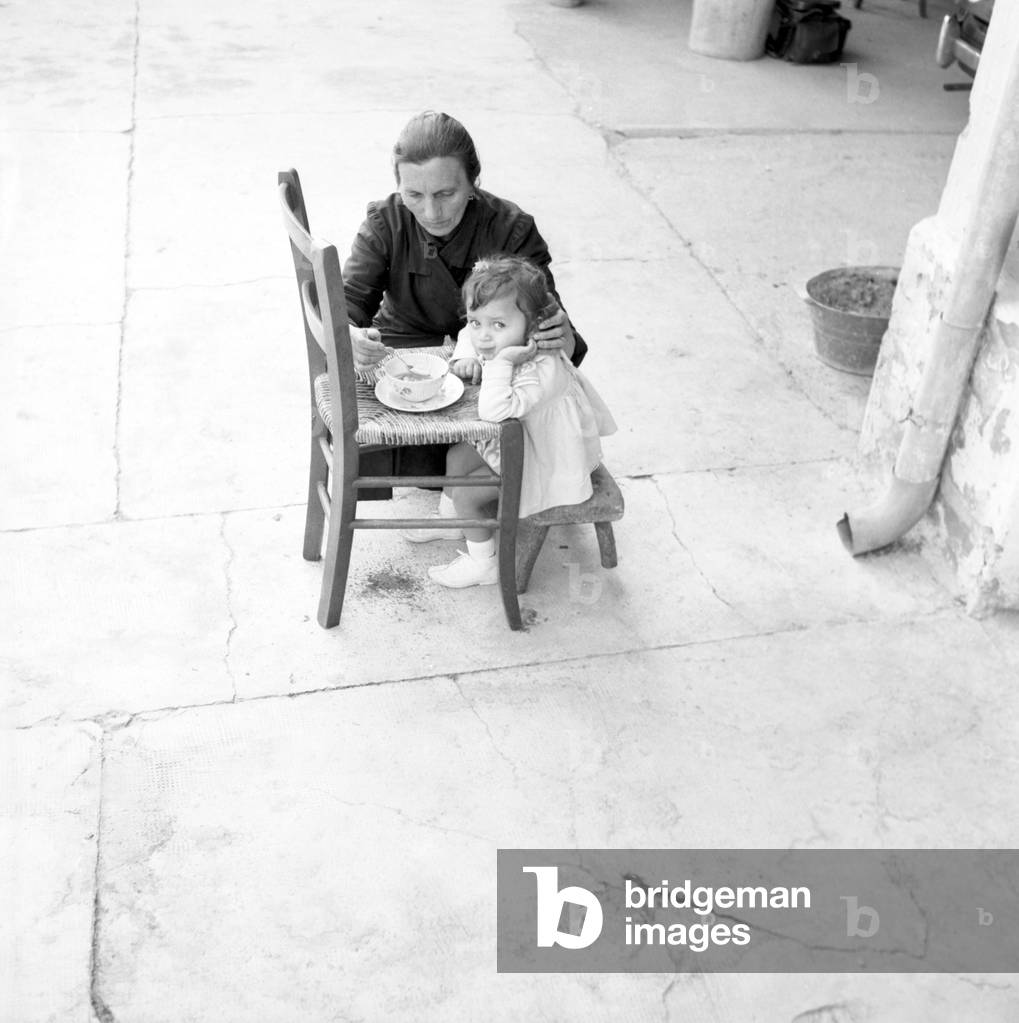 Rovereto di Credera Rubbiano , Italie 07/06/1962 Une grand-mere donne a sa petite-fille a manger (A grandma feeds her granddaughter) Photographie 