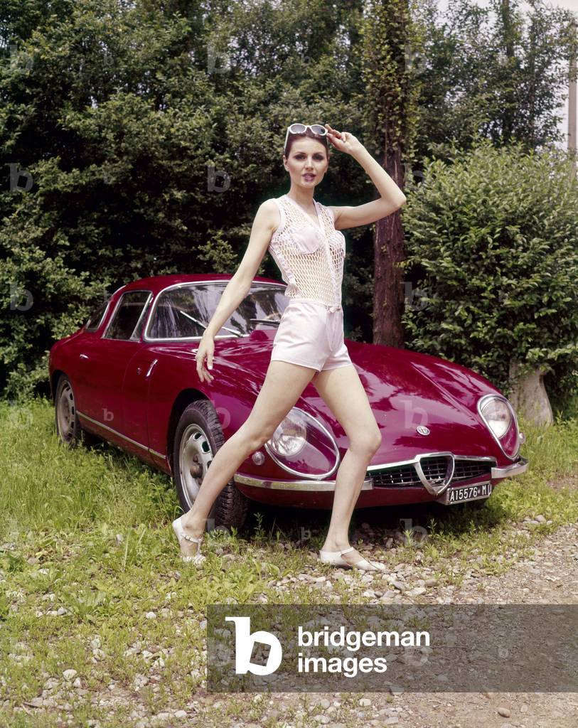 A model posing in front of an Alfa Romeo Giulia TZ Zagato, 1965 (photo)