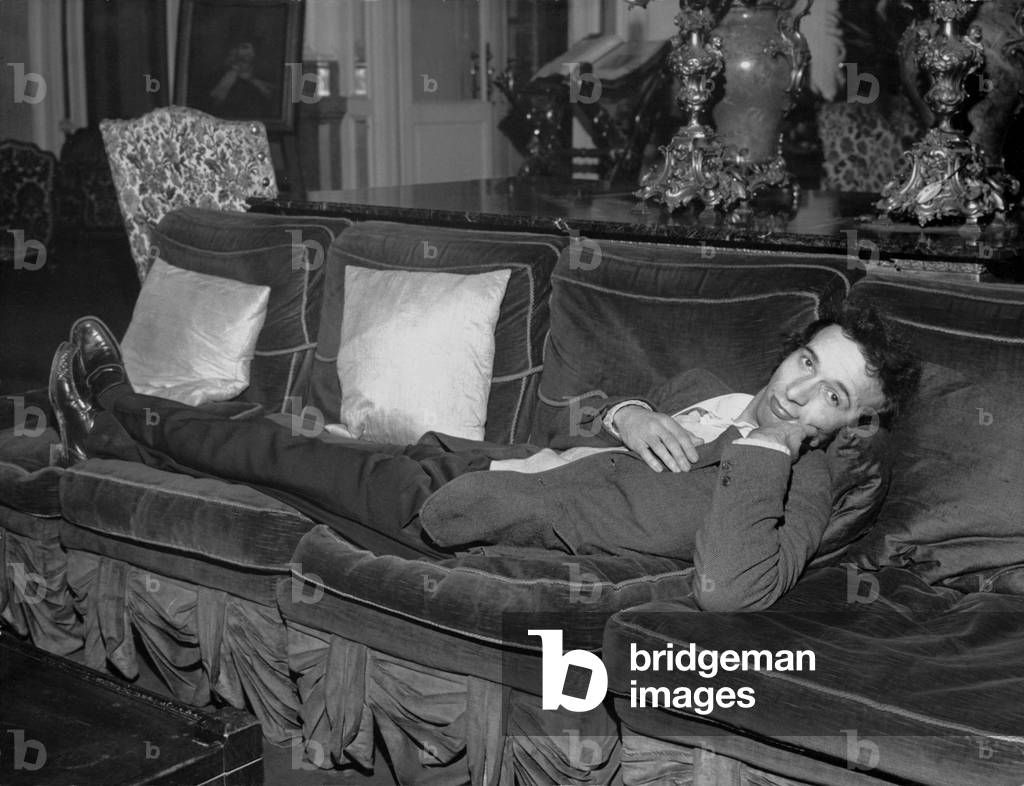Roberto Benigni lying on a velvet couch at the Porta Romana Theatre, Milan, 1979 (b/w photo)
