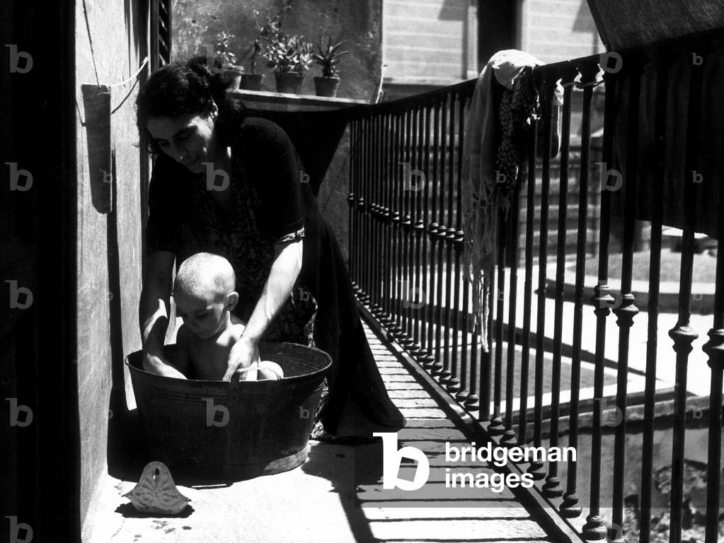 A mother bathing her child on the balcony, Milan, 1947 (b/w photo)