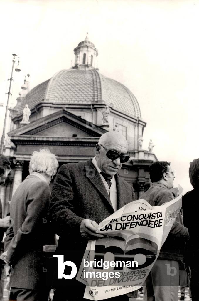 A passer-by reading a daily newspaper propagating the referendum on the abolition of divorce, Rome, 1974 (b/w photo)