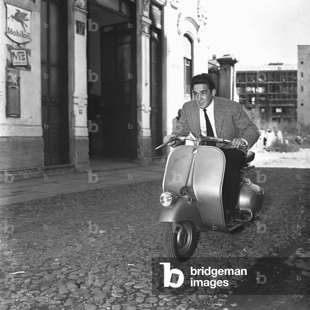 A young man driving a vespa in the streets of Milan, 1955 (b/w photo)