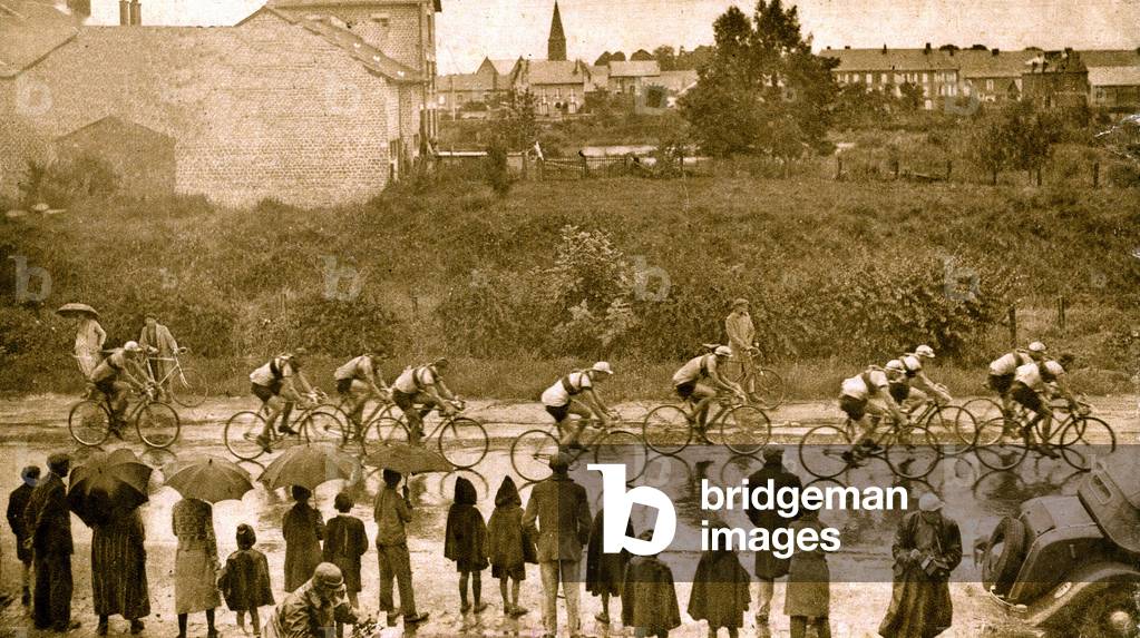 Tour de France cyclist 1936: the riders in the rain at Donchery, on the Montmedy road during the 3rd stage Charleville-Metz. Spectators under umbrellas. Photograph of the Mirror of Sports n°893 of July 11.