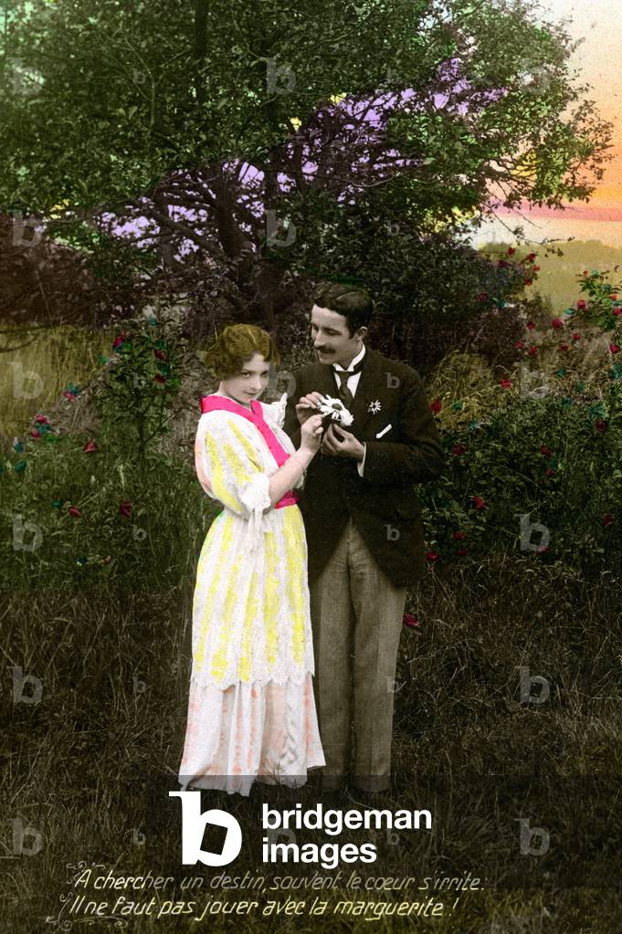 Couple of lovers efoliating the daisy in the countryside (nature). Legend in Alexandrins: “” Seeking a destiny, often the heart gets irritated - Do not play with the daisy””. Postcard beginning 20th century