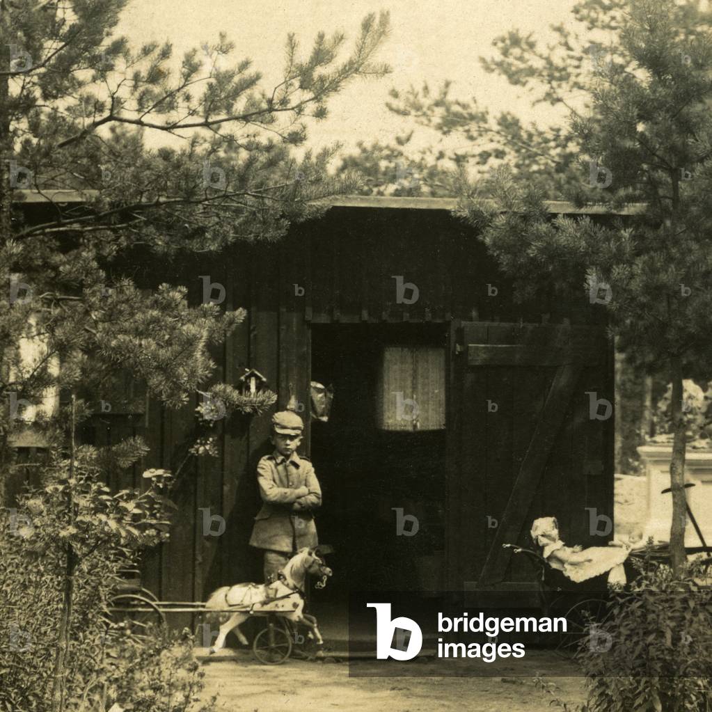 First World War 14-18 (1914-1918) - a young boy poses for photography with his toys in front of a garden shed, wearing a military uniform of his size and wearing a pointed helmet - The father of the child, absent in the photo, probably left for war - detail of an original photographic print of the period - soldier of the army German -