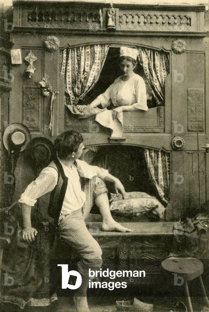 Picturesque Brittany: couple in a closed bed, traditional Breton furniture with 2 floor. Postcard beginning 20th century.