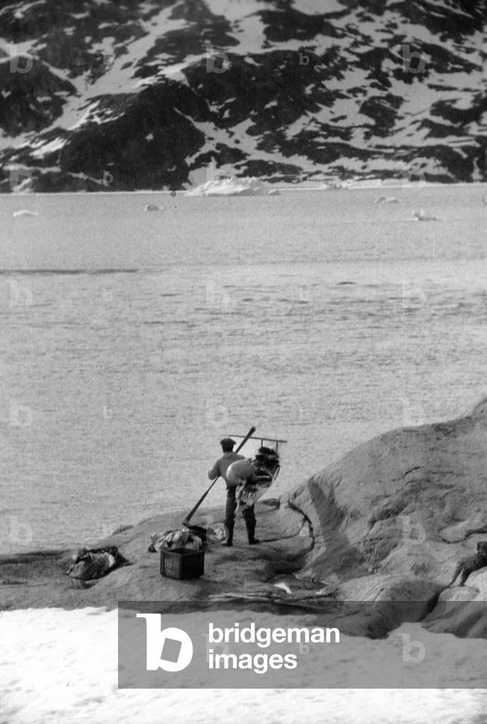 Inuit coming back from hunting, during polar expedition in Greenland, Kangerdlugssuatsiak, Summer, 1936 (b/w photo)