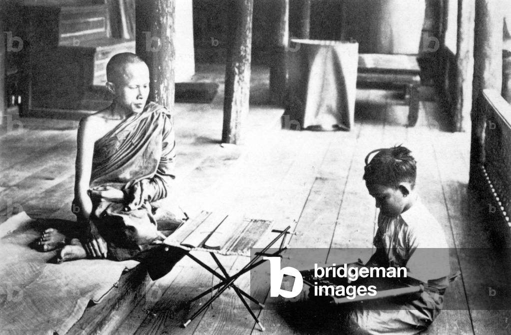 Thailand: A 1900 photograph of a Buddhist monk teaching a child in Nakhon Phanom in Isarn, northeastern Siam.