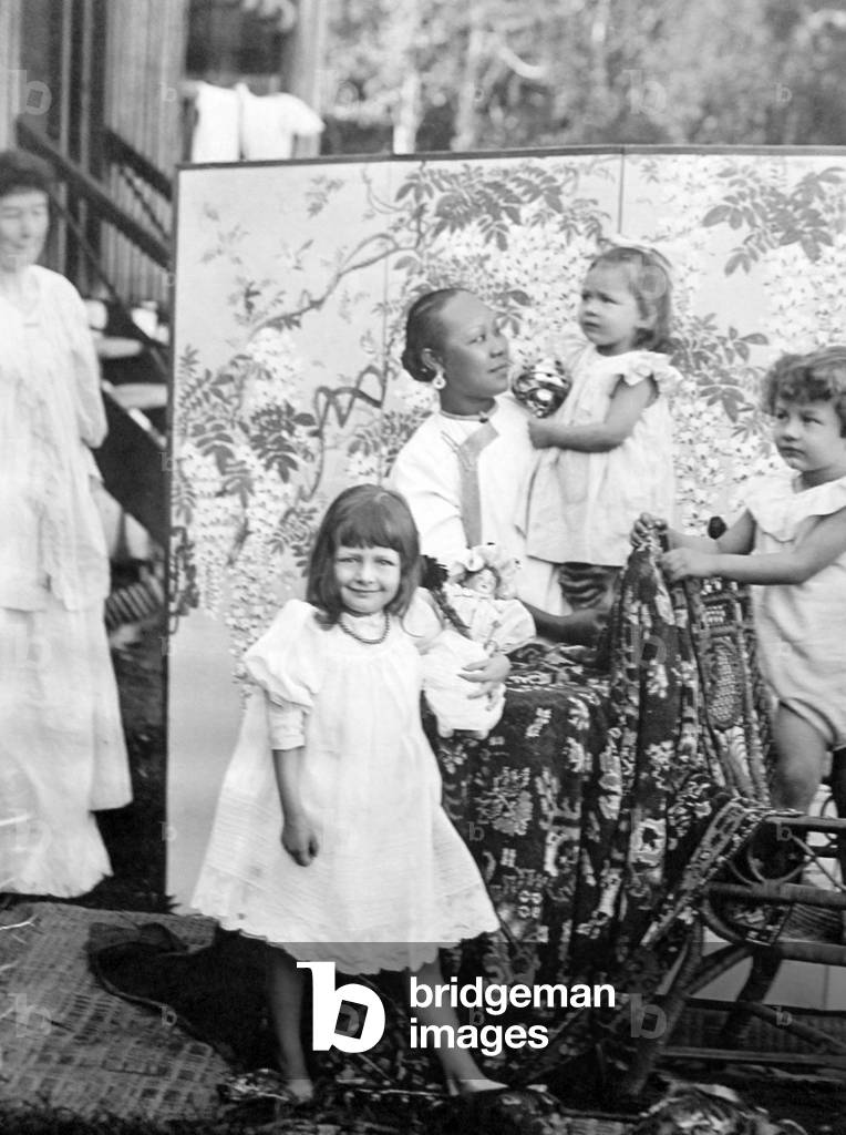 Singapore: An Amah posing with European children as the European 'Mem' looks on, c. 1900.