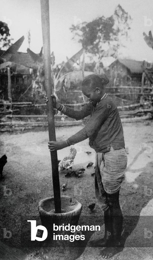 Vietnam: A young woman husks rice with a mortar and pestle in the Mekong Delta, Cochinchina, in 1930.