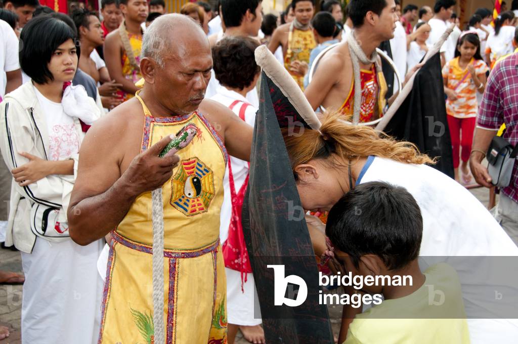 Thailand: A 'Ma Song' (entranced devotee) blesses a mother and son at San Chao Chui Tui (Chinese Taoist temple), Phuket Vegetarian Festival