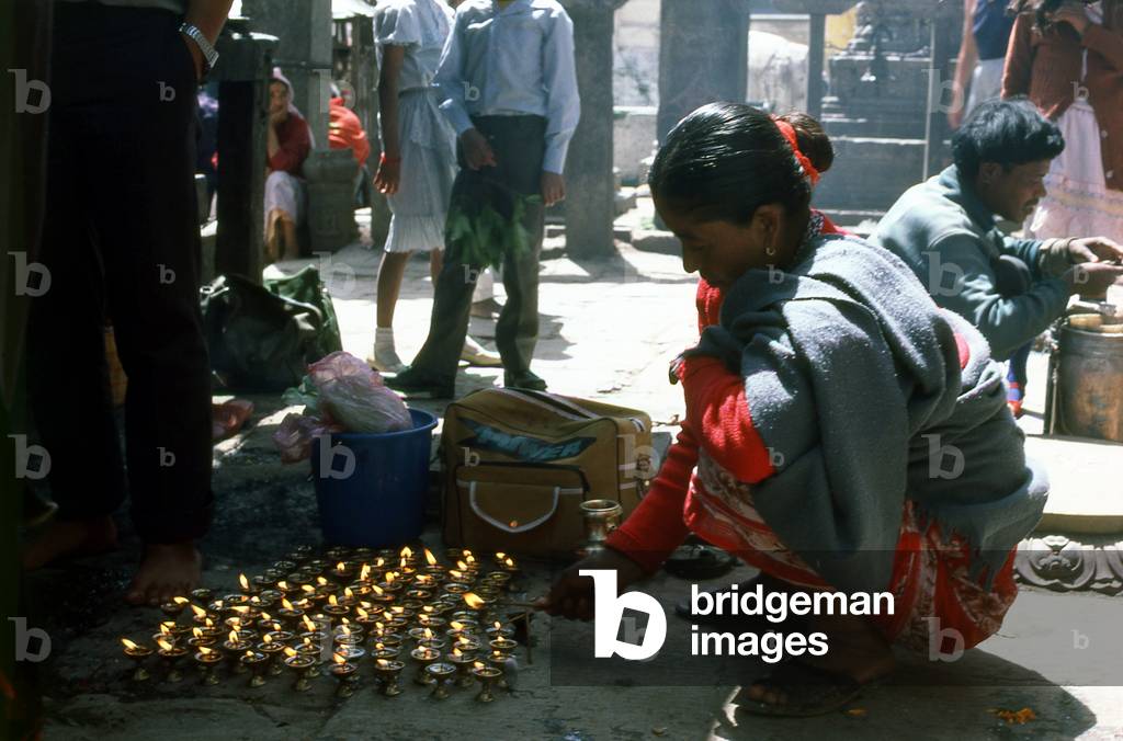 Nepal: A pilgrim lights oil candles to earn merit at Swayambhunath (Monkey Temple), Kathmandu Valley