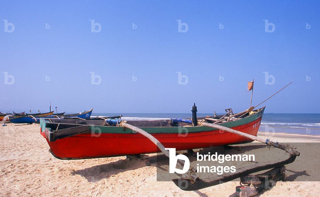 India: A traditional Goan outrigger fishing boat sits on the beach at Benaulim Beach, South Goa