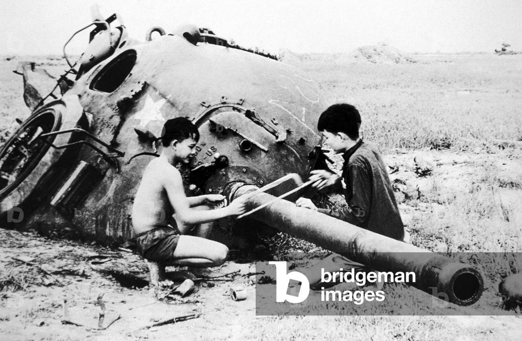 Vietnam: NLF children sawing barrel off destroyed US tank, Cu Chi, 1968