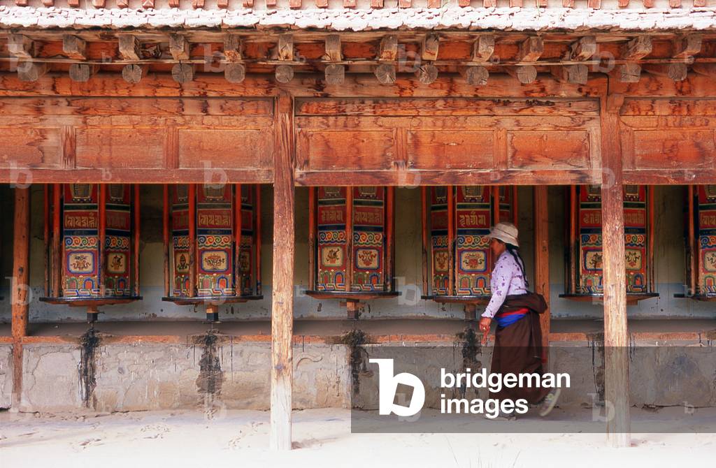 China: A pilgrim makes a circuit of the monastery turning each of the prayer wheels, Labrang Monastery, Xiahe, Gansu Province
