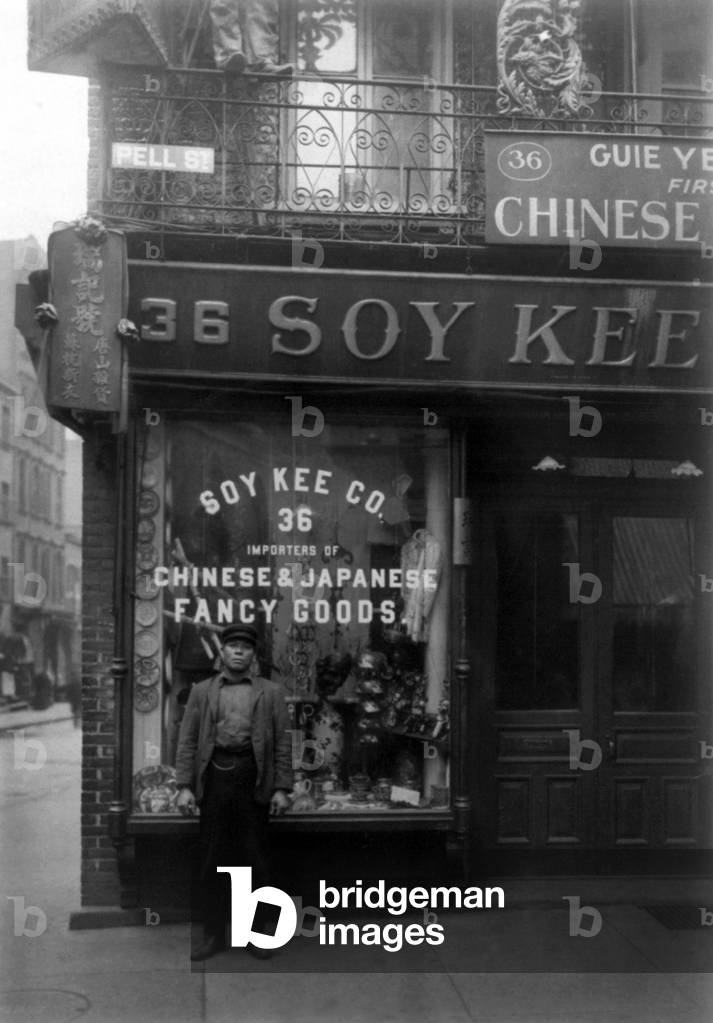 USA: Chinese man standing outside 36 Pell Street, New York Chinatown, early 20th century