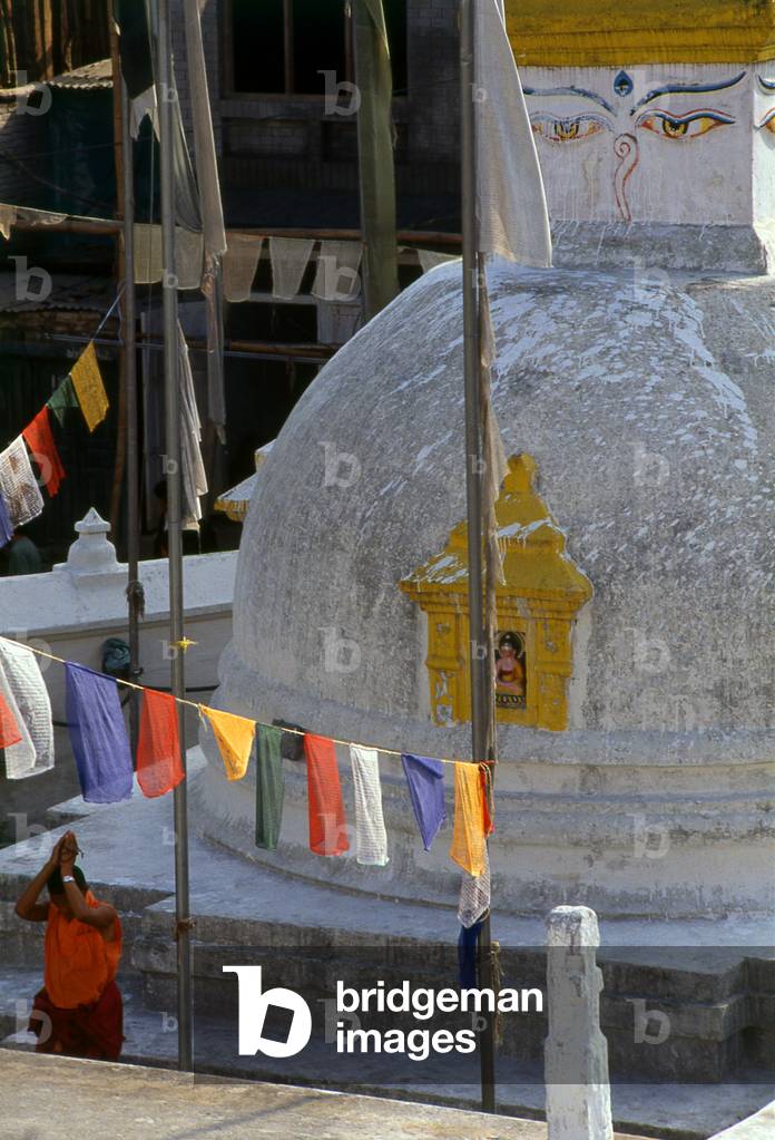 Nepal: A monk prays next to a small stupa at Bodhnath (Boudhanath), Kathmandu