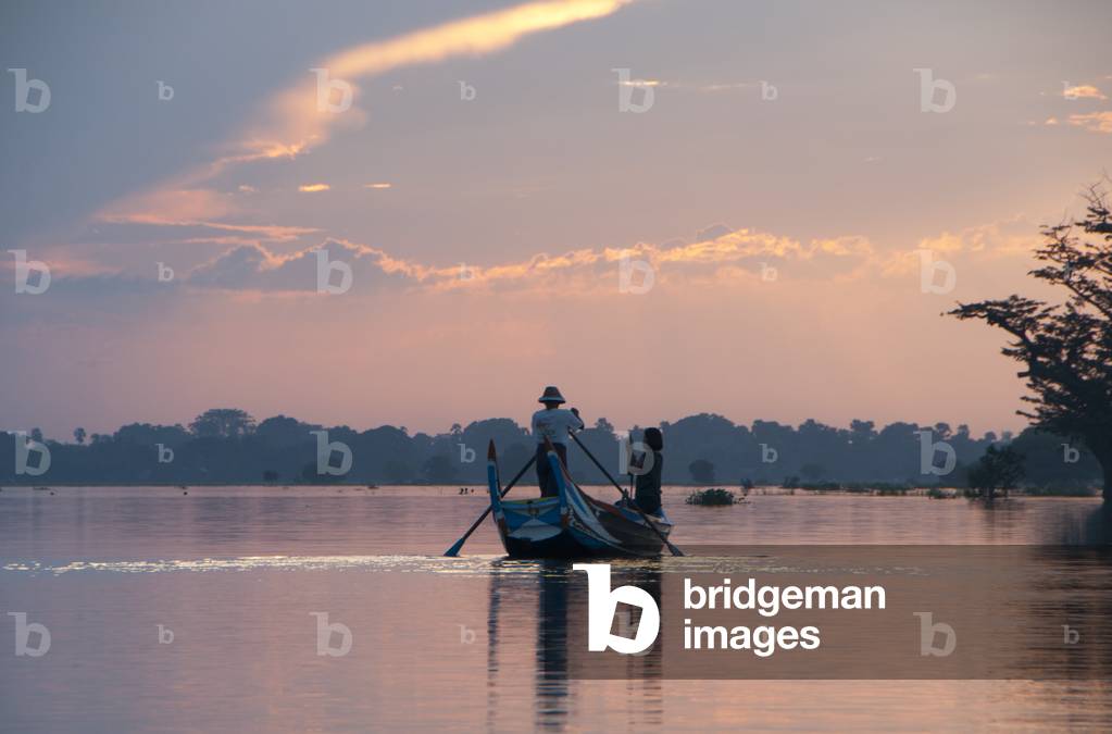 Burma / Myanmar: At sunset a boatman steers tourists close to the U Bein Bridge, the longest teakwood bridge in the world, Taungthaman Lake, near Amarapura, Mandalay
