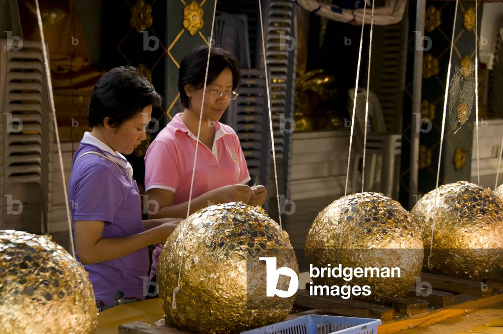 Thailand: Women plastering gold leaf on luk nimit (holy stone spheres), Wat Phrathat Doi Kham, Chiang Mai