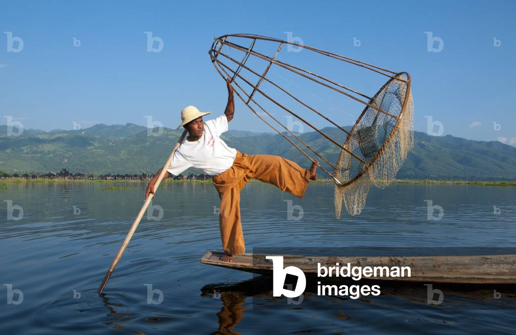 Burma / Myanmar: A leg rowing Intha fisherman shows off his skills with a large conical fish trap at Inle Lake, Shan State